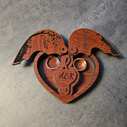 A close-up of a custom engraved wedding ring box in heart shape with both lids open, revealing two inner ring slots and personalized initials (A&K). This wooden ring holder is perfect for weddings, proposals, engagement shoots, or anniversary celebrations. A romantic gift box, laser cut from natural wood, ideal as a unique keepsake box for couples. Popular as a rustic wedding ring box, engraved engagement gift, or couple’s anniversary present.