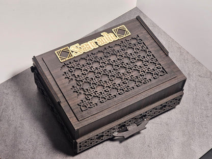 Closed chocolate box made of walnut wood with laser-cut design and custom gold nameplate on top, shown on a grey background.