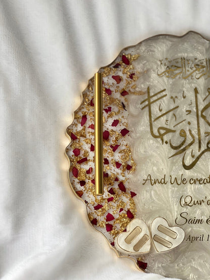Close-up of engagement tray with engraved names and heart-shaped ring slot, decorated with dried petals and luxury epoxy finish