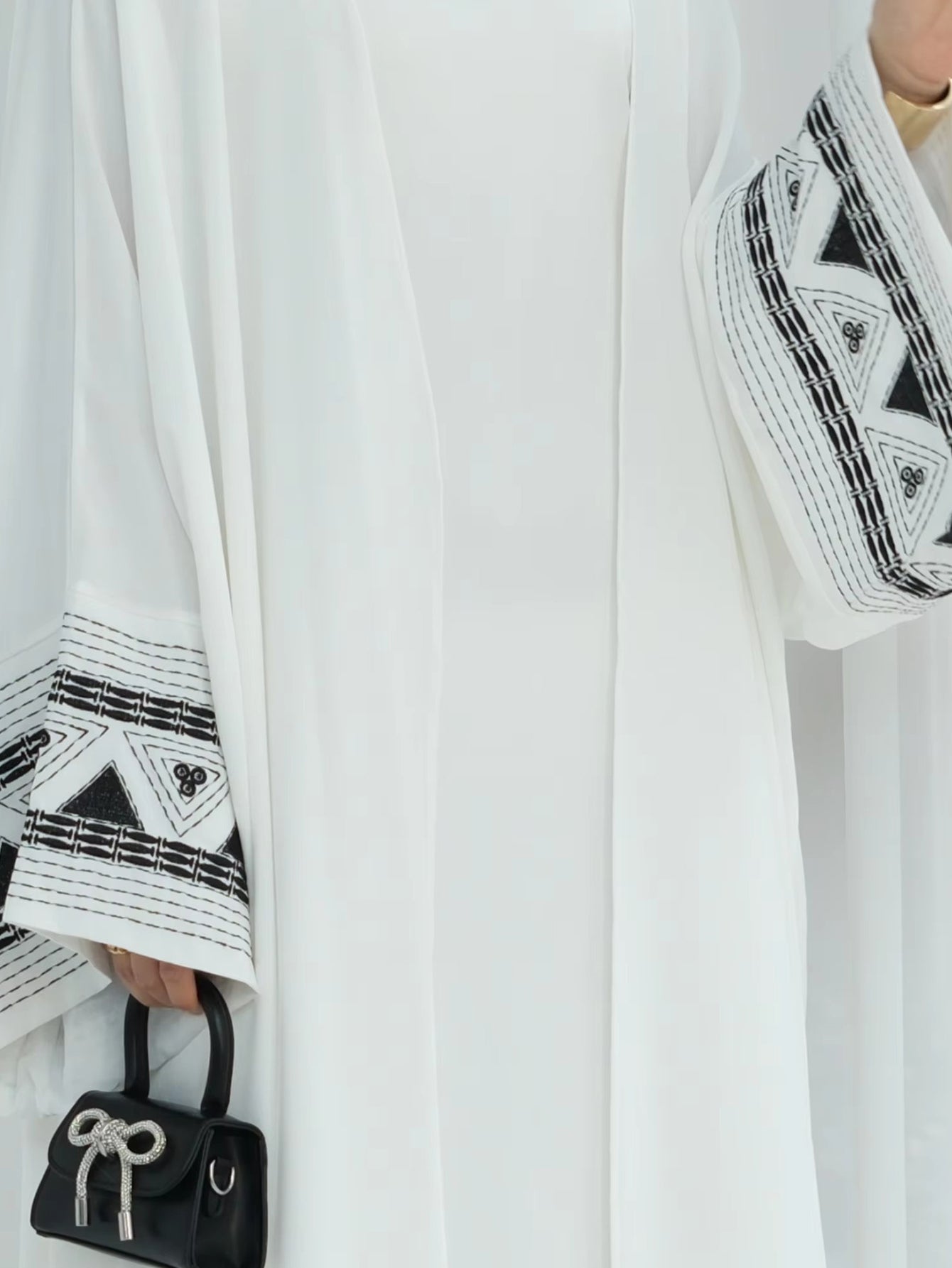 Close-up of white abaya sleeve with black embroidery – luxury modest fashion detail