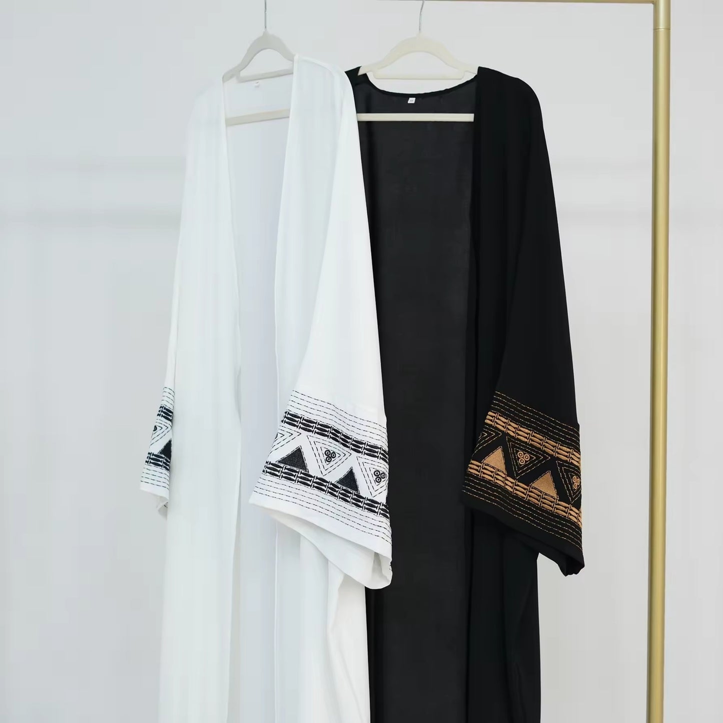White and black abayas hanging on rack – Islamic clothing for women – Dubai style modest wear