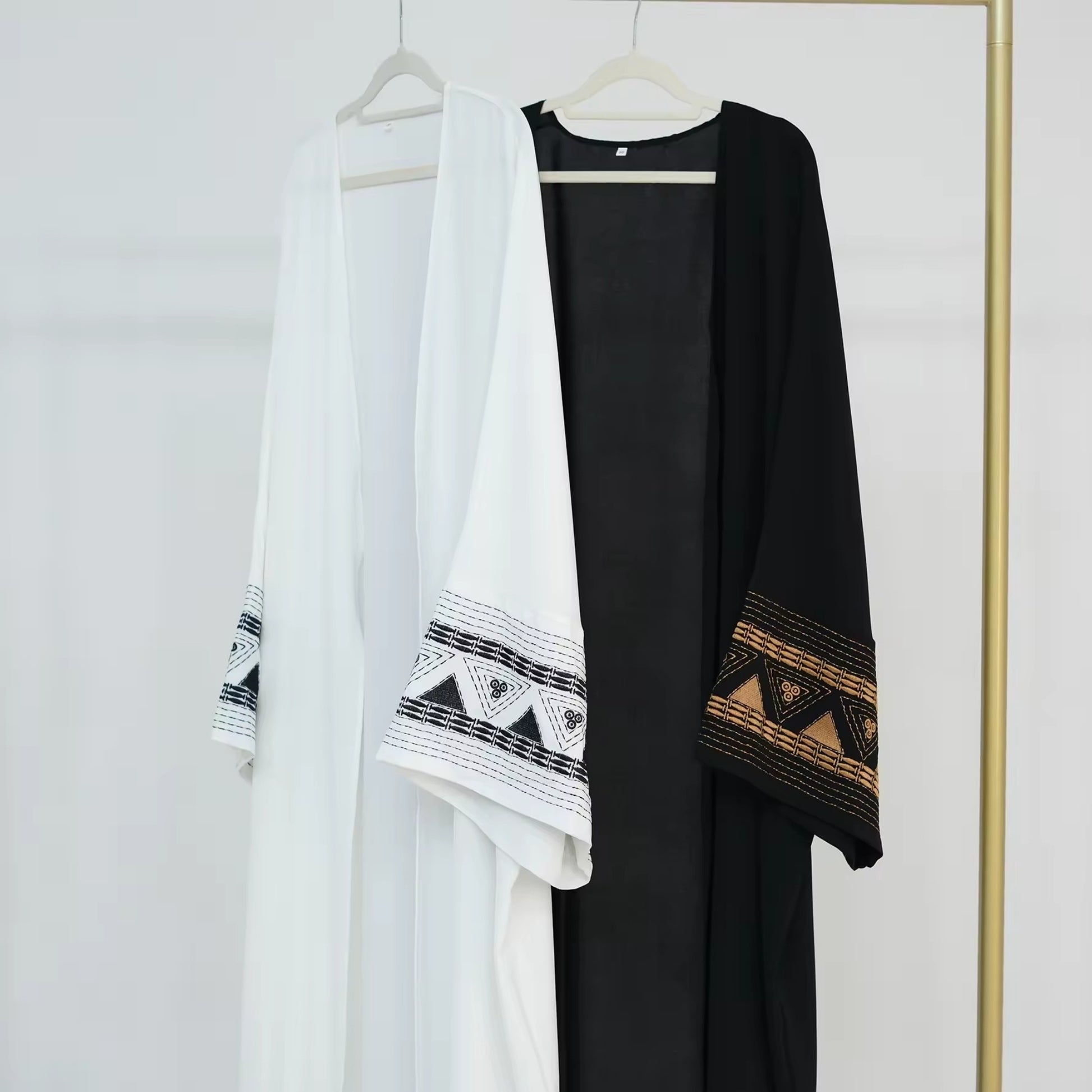 White and black abayas hanging on rack – Islamic clothing for women – Dubai style modest wear