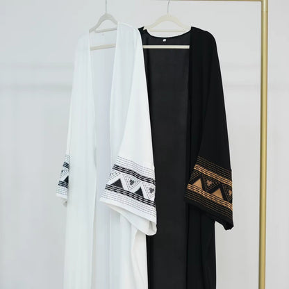 White and black abayas hanging on rack – Islamic clothing for women – Dubai style modest wear